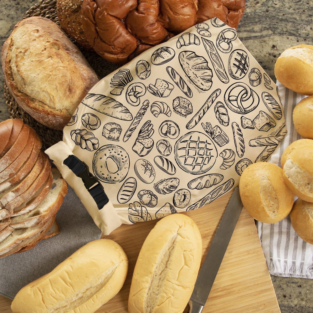 Think4Earth Reusable Bread Bag in beige with a black buckle closure and a pattern of various baked goods. Made from recycled plastic bottles.